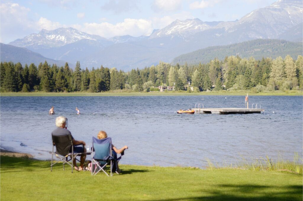 elderly couple in lawn chairs looking at lake with mountain views